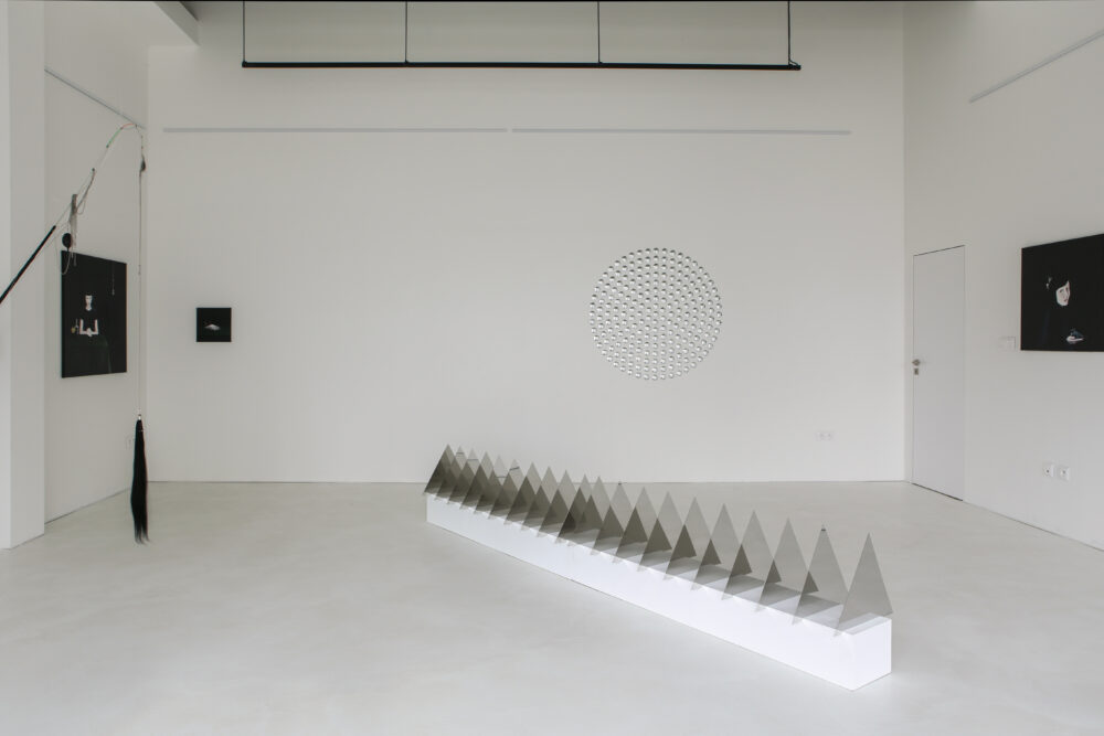 Infinity Mirroring, 2023, Installation view, Station Gallery, Bratislava (collaboration with Iskra Blagoeva) The installation at Station Contemporary Art Gallery talks about this state of confusion, the constant multiplication and transmission of the reflection of the phenomena depicted, along with their deformation and deconstruction. To this effect, it combines the natural optical effects of Stella Vasileva’s object-based work, which materializes light (and which can also be considered a symbolic entity) in combination with mirrors, transparent materials or tanks of water, with the paintings and objects of Iskra Blagoeva, whose work is infused with a reassessment and reinterpretation of the mythological foundations of our patriarchally-oriented culture. In contrast, Vasileva’s work is more meditative, immersed in the analysis of natural laws. She focuses on light, its impact and rhythm, which she thematizes in geometric structures. Their overlaps cooperate and establish a dialogue with their surroundings - the gallery space and other works. It is the interplay between social patterns and the physical nature of mirroring that reveals how the principles of the propagation of norms resemble the propagation of light or reflections in nature. Indeed, mirroring in psychology can also be understood as the instinctive imitation of others behavior in social interactions. On a societal scale, therefore, a form of a kind of social mirroring can be considered. Curated by Jana Babušiaková